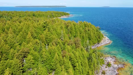 Aerial-drone-shot-following-the-beautiful-coastline-and-crystal-clear-blue-water-of-Georgian-Bay,-Ontario,-Canada
