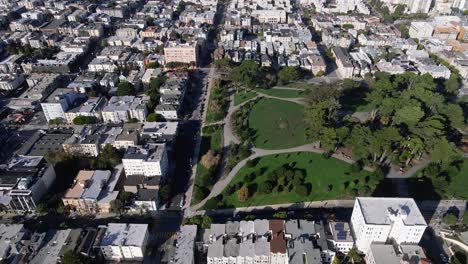 Aerial-view-of-Alamo-Square-Park-in-San-Francisco,-showcasing-the-lush-greenery-and-iconic-Victorian-houses