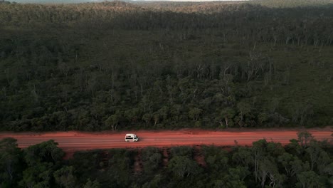 Toma-De-Drone-De-Una-Camioneta-Conduciendo-Por-Un-Camino-De-Tierra-Roja-En-Medio-Del-Monte-Australiano-En-Australia-Occidental