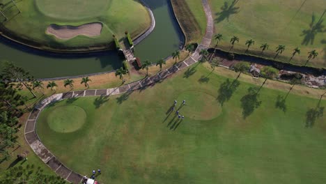 Drone-shot-from-above,-top-to-bottom-footage-shows-a-golfer-taking-a-tee-shot