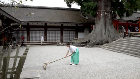 Monk-Using-Traditional-Wooden-Rake-On-Gravel-Garden-At-Kasugataisha-Shrine