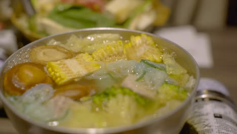 Various-vegetables-bubbling-in-boiling-hot-asian-hotpot-soup,-filmed-as-slow-motion-close-up-shot