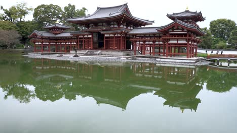 Tilt-Up-From-Reflection-Of-Byodo-In-On-Pond-Lake-Surrounded-It-In-Uji-To-Reveal-The-Phoenix-Hall