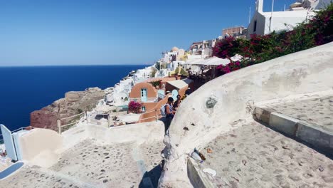 Oia-Santorini-Greece-Island-Travel-Tourist-Immersive-Walk,-Europe,-4K-|-Greek,-Aegean,-Sea,-Cliffside,-Ocean,-City,-Vacation,-Shopping,-White,-Marble,-Crowd,-Flowers,-Traveler,-People,-Stairs,-View