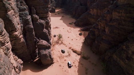 Drone-Shot-Of-Vehicles-Driving-Through-Sahara-Desert-In-Tassili-N'Ajjer-National-Park,-Algeria