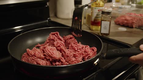 Female-breaks-up-ground-beef-as-it-cooks-on-a-frying-pan