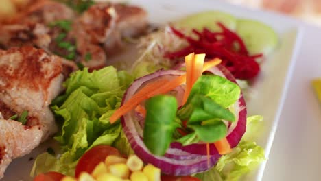 Delicious-pork-pieces-and-fresh-salad-served-at-restaurant,-close-up
