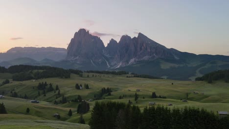 Timelapse-shot-with-drone-about-green-field-and-big-mountains-in-the-background-in-the-Italian-Alps,-Dolomites-during-sunrise