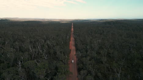 Disparo-De-Un-Dron-Sobre-Una-Furgoneta-Conduciendo-Por-Un-Camino-De-Tierra-Rojo-Australiano-A-Través-De-Los-Arbustos-En-Australia-Occidental