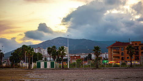 Ein-Zeitraffer-Eines-Sonnenuntergangs-Mit-Dramatischen-Wolken-In-Einer-Stadt-In-Der-Nähe-Eines-Berges-In-Spanien