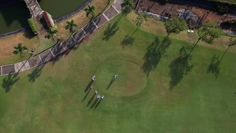 Drone-shot-from-above,-top-to-bottom-footage-shows-a-golfer-taking-a-tee-shot