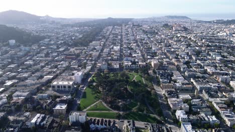 Aerial-view-of-Alamo-Square-Park-in-San-Francisco,-showcasing-the-lush-greenery-and-iconic-Victorian-houses