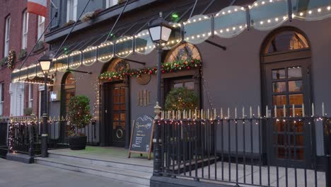 Shot-of-locals-walking-past-the-entrance-of-the-Harcourt-Hotel-beautifully-lit-up-with-Christmas-decorations-in-Dublin,-Ireland