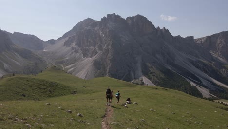 Excursionistas-Caminando-Por-Las-Montañas,-Una-Gran-Montaña-Al-Fondo-Filmada-Con-Un-Dron-En-Los-Alpes-Italianos,-Dolomitas