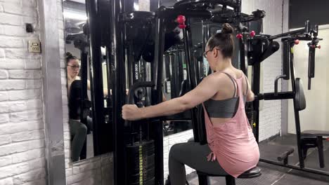 Young-woman-doing-arm-muscle-strengthening-exercises-in-front-of-the-mirror-in-the-gym,-doing-arm-strengthening-movements