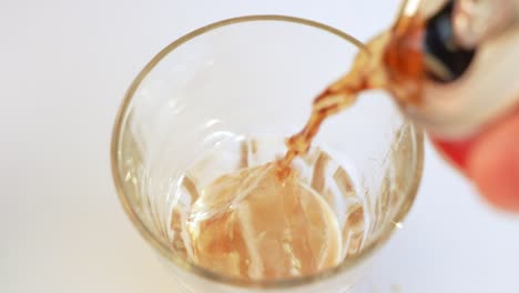 Pouring-cola-into-glass-with-ice-cubes-on-white-background
