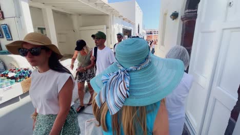 Oia-Santorini-Greece-Island-Travel-Tourist-Immersive-Walk,-Europe,-4K-|-Greek,-Aegean,-Sea,-Cliffside,-Ocean,-City,-Vacation,-Shopping,-White,-Marble,-Crowd,-Flowers,-Traveler,-People,-Hat,-Narrow