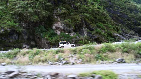Toma-Aérea-De-Seguimiento-De-Un-Jeep-Todoterreno-Que-Conduce-A-Turistas-Por-Una-Peligrosa-Y-Escarpada-Carretera-De-Montaña-Hacia-Jomsom,-Nepal.