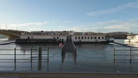Tilt-Locked-Pedestal-shot-of-the-Danube-River-Flooding-at-Dock-9-of-Carl-Lutz-Quay,-Budapest,-Hungary---December-26,-2023