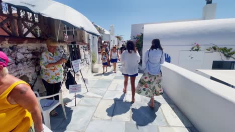 Oia-Santorini-Greece-Island-Travel-Tourist-Immersive-Walk,-Europe,-4K-|-Greek,-Aegean,-Sea,-Cliffside,-Ocean,-City,-Vacation,-Shopping,-White,-Marble,-Crowd,-Flowers,-Traveler,-People,-Busy,-Windy