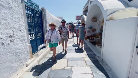 Oia-Santorini-Greece-Island-Travel-Tourist-Immersive-Walk,-Europe,-4K-|-Greek,-Aegean,-Sea,-Cliffside,-Ocean,-City,-Vacation,-Shopping,-White,-Marble,-Crowd,-Flowers,-Traveler,-People,-Alley,-Path
