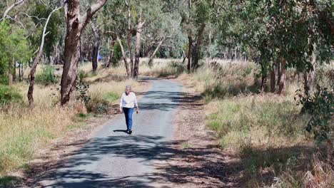 Senior-woman-walking-along-a-bike-and-cycle-track-beside-Lake-Mulwala,-NSW,-Australia