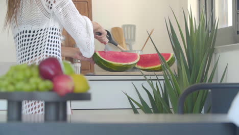 Eine-Frau-Im-Weißen-Kleid-Schneidet-Reife-Rote-Wassermelone-Mit-Einem-Großen-Messer