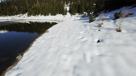 FPV-drone-flight-over-frozen-mountain-lake,-high-speed-flyover-winter-nature-scene