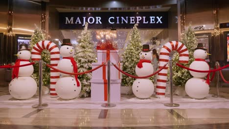 Christmas-decorations-of-trees,-candy-canes,-snowmen,-and-gigantic-gifts-placed-in-front-of-a-movie-theater-in-Bangkok,-Thailand