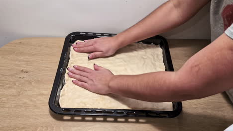 A-Time-Lapse-Of-Two-People-Greasing-A-Tin-And-Placing-Dough-And-Vegetables