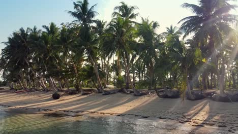 Sonneneruption-Durch-Kokospalmen,-Die-Sich-Bei-Sonnenuntergang-Zum-Strand-Neigen