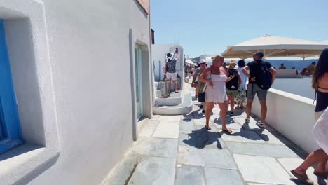 Oia-Santorini-Greece-Island-Travel-Tourist-Immersive-Walk,-Europe,-4K-|-Greek,-Aegean,-Sea,-Cliffside,-Ocean,-City,-Vacation,-Shopping,-White,-Marble,-Crowd,-Flowers,-Traveler,-People,-Family,Backpack