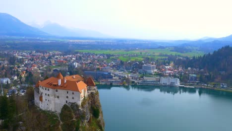 Drone-backwards-left-rotating-view-of-lake-Bled-island-and-castle-reveal
