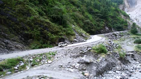 Antena-De-Un-Jeep-Safari-4x4-Que-Transporta-Turistas-Fuera-De-La-Carretera-Por-Un-Paisaje-Verde-De-Montañas-Rocosas-En-Mustang-Nepal