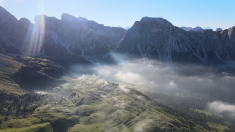 Nebel,-Der-Mit-Einer-Drohne-Von-Oben-über-Den-Wolken-Gefilmt-Wurde,-Während-Im-Hintergrund-Berge-Während-Des-Sonnenaufgangs-In-Den-Italienischen-Alpen,-Dolomiten,-Zu-Sehen-Sind