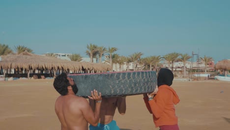 athletes-at-the-beach-lifting-a-huge-car-tire-up-to-heads---Slow-Motion