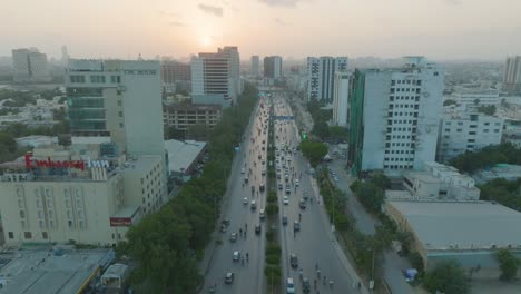A-drone-glides-through-the-city-skies-near-the-CDC-Building-in-Karachi,-Pakistan,-during-a-cloudy-evening-as-the-sun-sets
