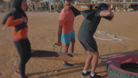 A-Hijabi-Athlete-Racing-By-the-beach-carrying-woods-and-sandbags---Slow-Motion