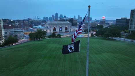 American-flag-and-POW-MIA-flag-waving-on-Liberty-Memorial-with-view-of-Union-Station-and-downtown-Kansas-City-at-dawn
