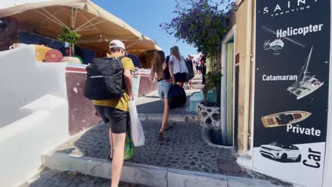 Oia-Santorini-Greece-Island-Travel-Tourist-Immersive-Walk,-Europe,-4K-|-Greek,-Aegean,-Sea,-Cliffside,-Ocean,-City,-Vacation,-Shopping,-White,-Marble,-Crowd,-Flowers,-Traveler,-People,-Cafe,-Sign