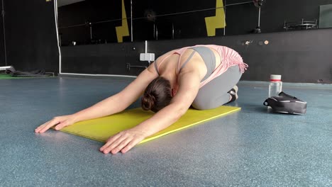 Young-fit-women-doing-yoga-doing-asanas-in-bright-yoga-studios,-yoga-a-form-of-physical-relaxation,-woman-lying-on-a-mat