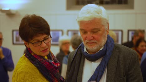 Older-man-with-white-hair,-scarf-and-beard,-and-brown-haired-senior-woman-view-object-close-up