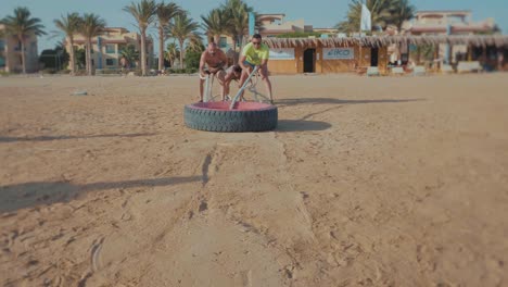 A-Group-Of-athletes-drags-a-huge-car-tire-by-the-beach---Front---Slow-Motion