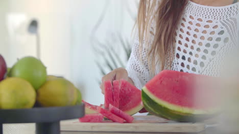 Female-hands-use-a-large-knife-to-cut-a-ripe-red-watermelon-into-even-pieces