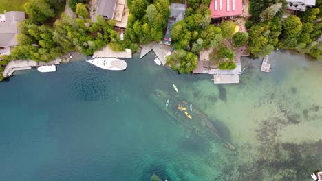Aerial-Top-Down-Shot-Kayakers-Joining-Together-on-top-of-a-Shipwreck-on-Big-Tub-Harbor,-Bruce-Peninsula,-Georgian-Bay