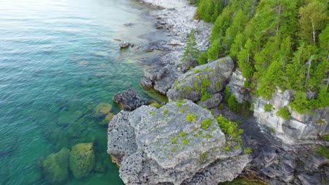Aerial-view-of-the-rocky-coast-with-turquoise-waters-on-the-shores-of-Georgian-Bay,-Ontario,-Canada