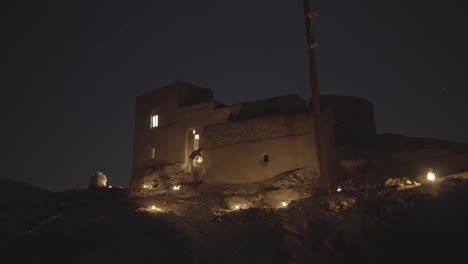 Old-house-traditional-local-historical-architecture-design-of-a-house-in-desert-at-night-the-stars-blinking-the-oil-lantern-light-top-of-the-hill-evening-time-astronomy-travel-for-galaxy-photography