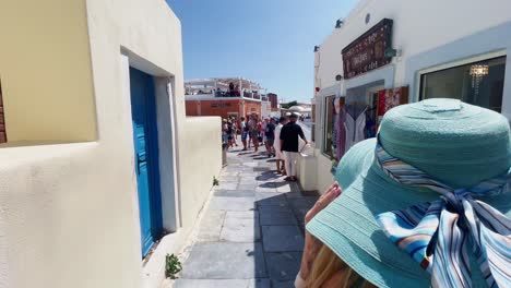Oia-Santorini-Greece-Island-Travel-Tourist-Immersive-Walk,-Europe,-4K-|-Greek,-Aegean,-Sea,-Cliffside,-Ocean,-City,-Vacation,-Shopping,-White,-Marble,-Crowd,-Flowers,-Traveler,-People,-Hat,-Path,-Busy