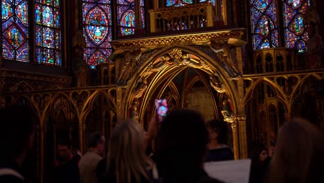 Cinematic-view-of-tourists-taking-pictures-of-the-ceiling-of-the-upper-chapel-of-the-Sainte-Chapelle-Church-with-its-blue-and-purple-stained-glass-windows,-National-Monument-of-France