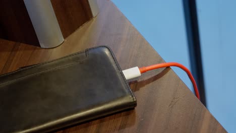 Red-usb-cable-inserted-to-phone-for-charging,-close-up